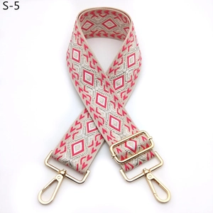 Detail of adjustable embroidered bag strap with geometric diamond patterns and gold buckles