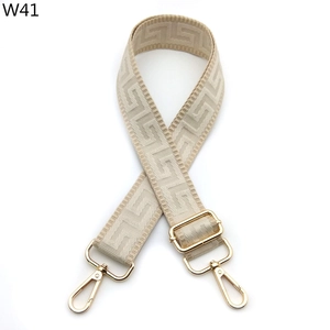 Adjustable beige woven bag strap with geometric patterns and golden metal buckles