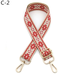 Detail of adjustable beige woven strap with red geometric pattern and gold metal hooks