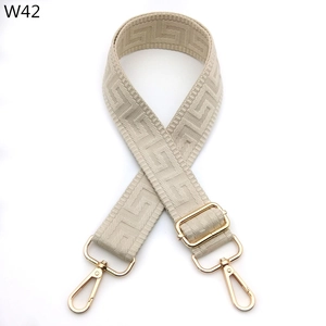 Detail of adjustable beige woven strap with golden metal hooks and jacquard pattern