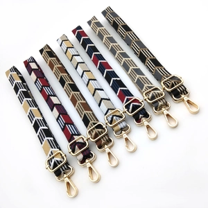 Detail view of woven bag straps with colorful arrow patterns and golden metal buckles