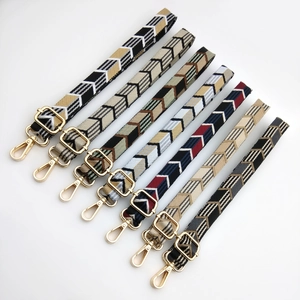 Close-up of assorted colorful geometric arrow woven straps with gold metal hooks and buckles
