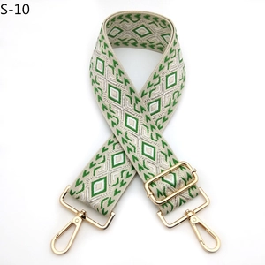 Macro view of green and beige geometric embroidery strap with light gold metal hardware