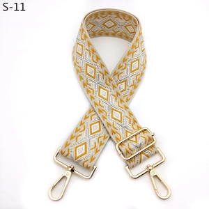 Detail of adjustable woven bag strap with yellow geometric pattern and gold metal hooks