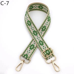Detail of green and white geometric jacquard bag strap with gold metal lobster clasps