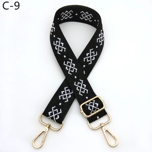Detail of black adjustable shoulder strap with white geometric jacquard pattern and gold hooks