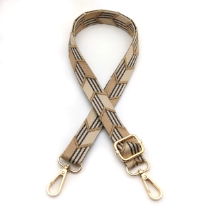 Close-up of beige geometric herringbone replacement bag strap with light gold hardware