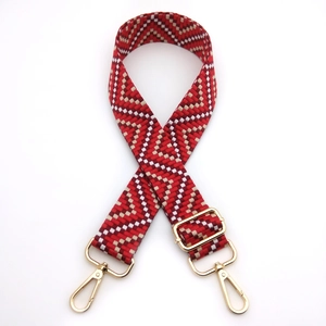 Adjustable wide woven guitar strap with red and white geometric patterns and gold clips
