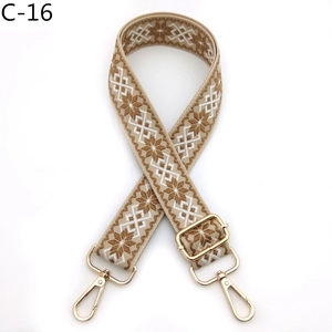 Detail of woven bag strap with brown snowflake pattern and gold metal spring buckles