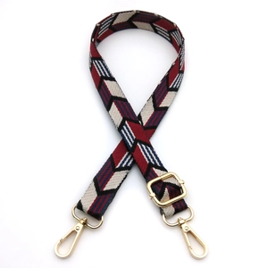 Close-up of adjustable woven shoulder strap with arrow pattern and gold metal lobster clasps