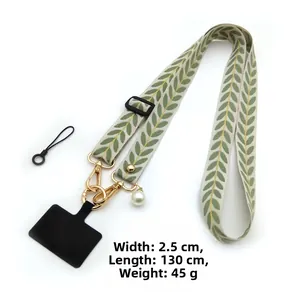 Detail of embroidered phone strap with green leaf pattern, pearl charm and metal hooks