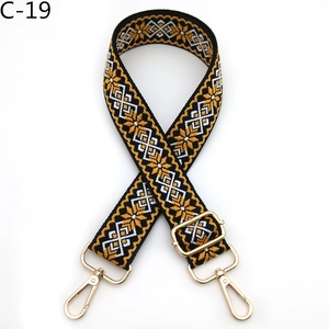 Detail view of ethnic embroidery pattern on adjustable crossbody bag strap with gold hardware