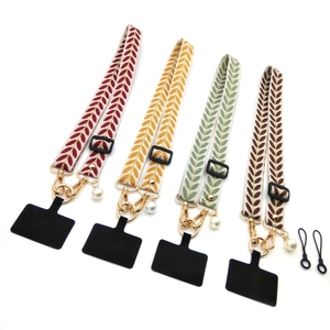 Detail of embroidered vine leaf phone straps with pearl charms and gold metal hooks