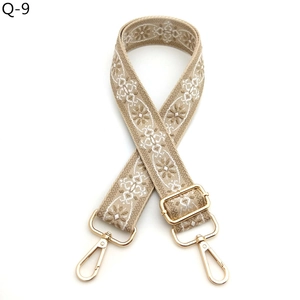 Close-up of ethnic style embroidered bag strap with floral patterns and gold hooks