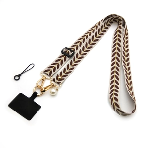 Detail of embroidered vine leaf phone strap with gold clasp and pearl pendant