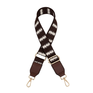 Detail of adjustable woven purse strap with brown faux leather and gold metal hardware