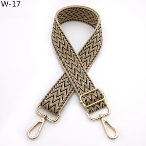 Detail of adjustable beige and black wave pattern woven bag strap with gold lobster clasps