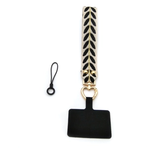 Detail of leaf pattern phone wrist strap with heart-shaped gold hook and black patch