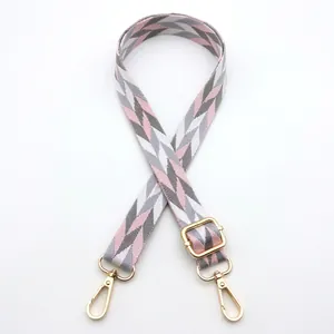 Detail of pink and grey herringbone woven strap with golden lobster clasps and metal buckle