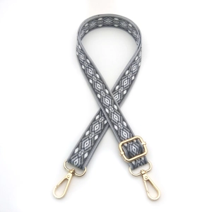 Detail of adjustable rhombus pattern bag strap with golden metal hooks and buckles
