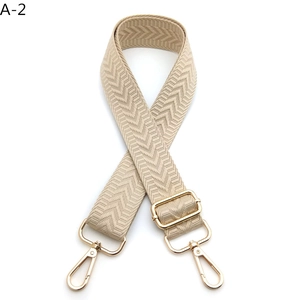 Detail of beige woven strap with chevron pattern and adjustable gold metal buckles