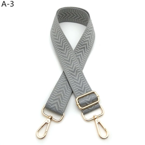 Detail view of adjustable grey chevron woven bag strap with polished light gold metal hooks