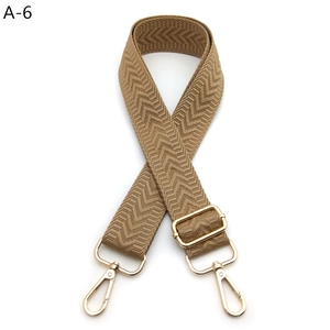 Detail of brown chevron woven bag strap with polished gold-tone metal hardware
