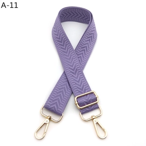 Detail of light purple woven shoulder strap with herringbone pattern and gold metal buckles