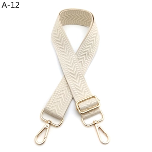 Detail showing adjustable wide jacquard woven strap with golden lobster clasps and beige chevron