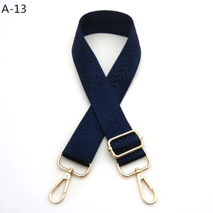 Detail of navy blue nylon bag strap with gold lobster clasps and herringbone pattern