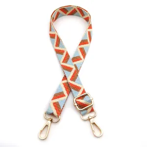Detail of adjustable geometric strap in light blue and orange with gold metal swivel hooks