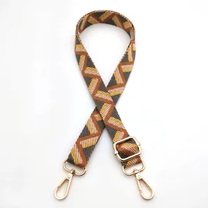 Detail of adjustable geometric patterned bag strap with gold metal hooks and buckle
