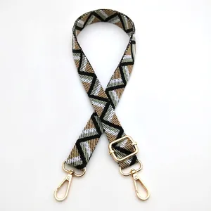 Detail of adjustable woven bag strap with geometric patterns and gold metal hooks