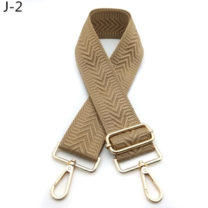 Detail of adjustable khaki herringbone woven bag strap with golden metal lobster clasps