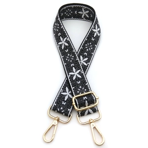 Detail view of adjustable ethnic style bag strap with white flower embroidery and gold buckles