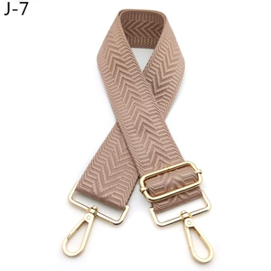 Close-up of brown herringbone shoulder strap with adjustable golden metal buckle and hooks