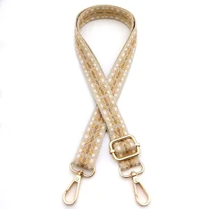 Close-up of geometric jacquard bag strap with gold metal hooks and adjustable buckle
