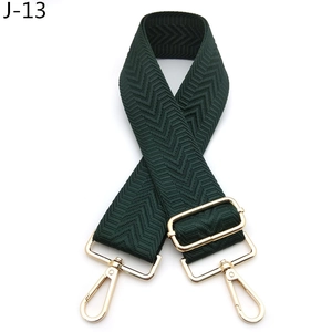 Close-up of dark green herringbone pattern bag strap with adjustable gold metal hardware