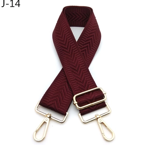 Detail of burgundy herringbone woven bag strap with polished gold metal buckles