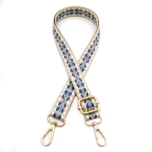 Detail of geometric pattern woven bag strap with adjustable gold buckle and spring hooks