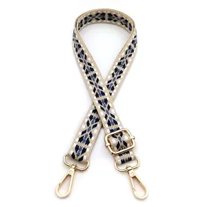 Close-up of beige and navy geometric woven bag strap with adjustable gold metal buckle