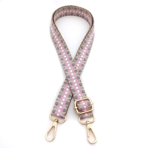 Dettaglio della tracolla tessuta con motivo geometrico rosa e fibbie in metallo oro