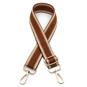 Detail of adjustable woven shoulder strap with brown wave pattern and gold metal hooks