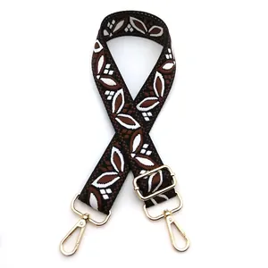 Detail of adjustable ethnic jacquard bag strap with white leaf pattern and gold buckles