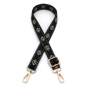 Detail of wide woven bag strap with white anchor patterns and gold lobster clasps