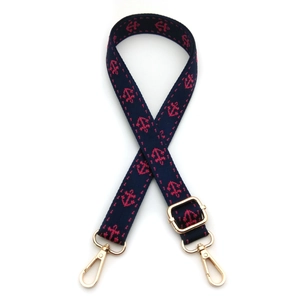 Detailed view of the navy blue woven strap with red anchor jacquard and gold metal clasps