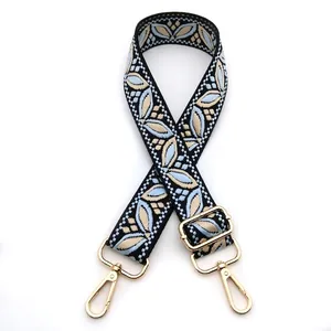 Detail of bohemian floral jacquard bag strap with gold lobster clasps and blue embroidery