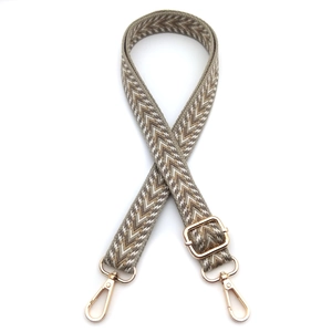 Detail of adjustable woven jacquard bag strap with geometric patterns and gold clips