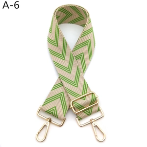 Detail of adjustable green chevron woven bag strap with golden metal lobster clasps