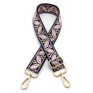 Detail of floral jacquard woven bag strap with golden metal swivel hooks and buckles
